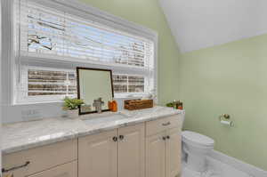 ADU Bathroom with tile patterned floors, vaulted ceiling, toilet, and vanity