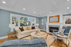 Living room with wood-type flooring, ornamental molding, and coffered ceiling