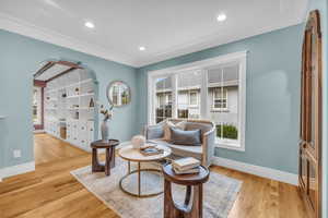 Sitting room with light wood-type flooring and ornamental molding