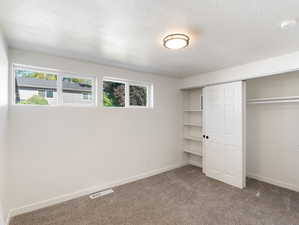 Unfurnished bedroom featuring carpet, a closet, and a textured ceiling