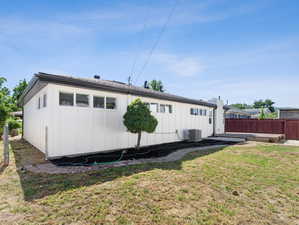 Rear view of house with a lawn and cooling unit