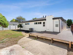 Rear view of house featuring a deck, central air condition unit, and a patio area