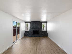 Unfurnished living room featuring hardwood / wood-style flooring and a stone fireplace