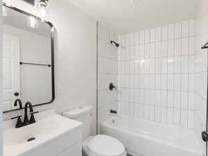 Full bathroom with toilet, vanity, and tiled shower / bath