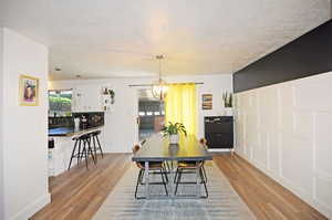 Dining space featuring a chandelier, light wood-type flooring, and a textured ceiling