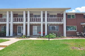 View of front facade with a balcony and a front lawn