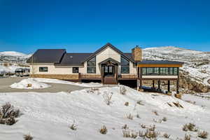 Snow covered rear of property with a wooden deck