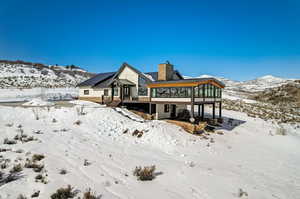 Snow covered back of property featuring a wooden deck