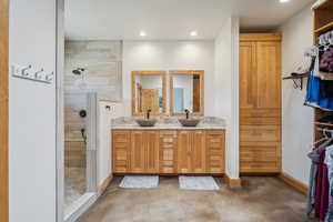 Bathroom featuring tiled shower and double sink vanity