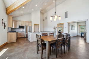 Dining room featuring an inviting chandelier, beamed ceiling, and high vaulted ceiling