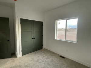 Unfurnished bedroom with light carpet and a closet