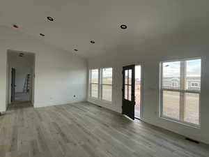 Unfurnished room with lofted ceiling, light wood-type flooring, and plenty of natural light