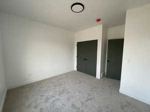 Unfurnished bedroom featuring a closet and light colored carpet