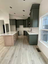 Kitchen with sink, a healthy amount of sunlight, lofted ceiling, and light wood-type flooring