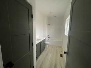 Full bathroom with wood-type flooring, toilet, vanity, and shower / tub combination