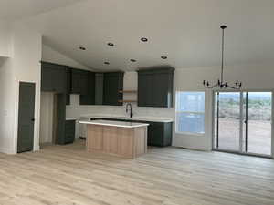 Kitchen featuring a chandelier, pendant lighting, sink, a kitchen island, and light hardwood / wood-style flooring