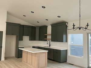 Kitchen featuring an inviting chandelier, a kitchen island, light hardwood / wood-style floors, pendant lighting, and sink