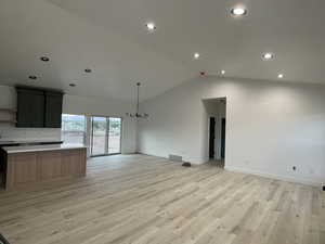 Unfurnished living room with lofted ceiling and light hardwood / wood-style flooring