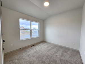 Empty room featuring carpet flooring and lofted ceiling