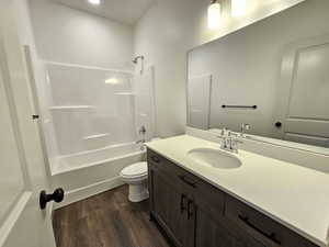 Full bathroom featuring vanity, toilet, hardwood / wood-style flooring, and bathtub / shower combination