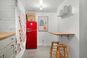 Kitchen featuring fridge and brick wall