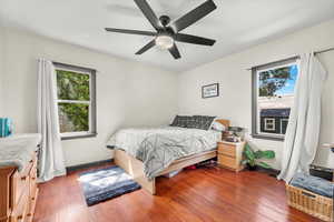 Bedroom with hardwood / wood-style flooring, multiple windows, and ceiling fan