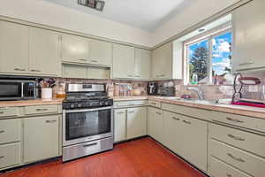 Kitchen featuring dark hardwood / wood-style flooring, crown molding, sink, appliances with stainless steel finishes, and backsplash