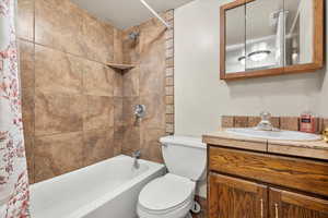 Full bathroom with vanity, shower / tub combo with curtain, and toilet