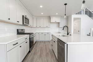 Kitchen featuring an island with sink, light countertops, light wood-style floors, stainless steel appliances, and a sink