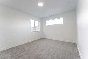 Carpeted spare room featuring visible vents and baseboards