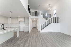 Kitchen featuring visible vents, light wood-style flooring, backsplash, an inviting chandelier, and hanging light fixtures