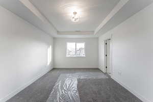 Spare room featuring a tray ceiling, visible vents, and baseboards