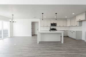 Kitchen featuring light wood finished floors, visible vents, light countertops, decorative backsplash, and stainless steel appliances