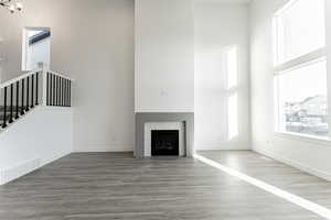 Unfurnished living room with stairs, visible vents, a towering ceiling, and a fireplace