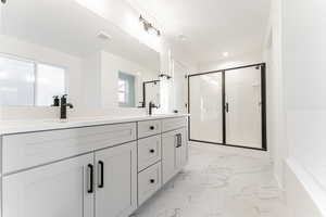 Full bathroom with a sink, marble finish floor, a shower stall, and double vanity