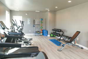 Gym with electric panel and light wood-type flooring