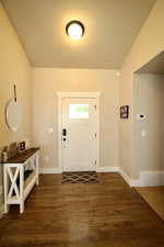 Foyer entrance with vaulted ceiling and dark hardwood / wood-style flooring