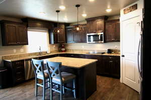 Kitchen with a center island, sink, dark hardwood / wood-style floors, and stainless steel appliances