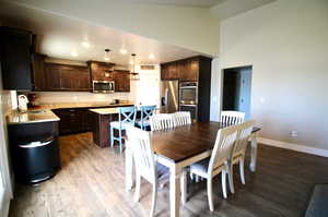 Dining space with high vaulted ceiling, sink, and wood-type flooring