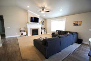 Living room featuring a fireplace, dark hardwood / wood-style floors, ceiling fan, and lofted ceiling