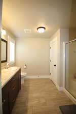 Bathroom featuring tile patterned floors, vanity, an enclosed shower, and toilet