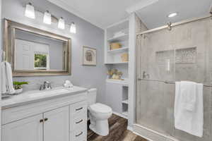 Bathroom featuring walk in shower, crown molding, toilet, vanity, and wood-type flooring