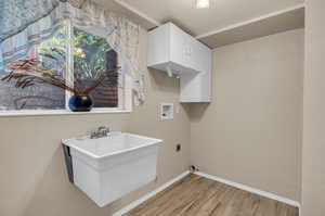 Washroom featuring hookup for a washing machine, light hardwood / wood-style floors, electric dryer hookup, and sink