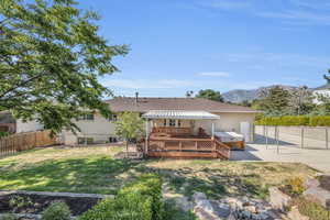 Back of property featuring a patio, a lawn, and a deck with mountain view