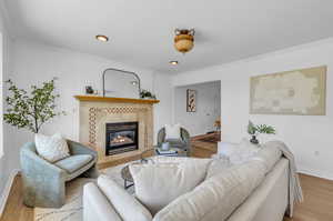 Living room featuring ornamental molding, a tile fireplace, and wood-type flooring