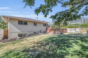 Back of house featuring cooling unit, a lawn, and a wooden deck