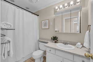 Bathroom featuring vanity, toilet, tile patterned floors, and crown molding