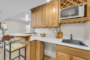 Kitchen featuring light hardwood / wood-style floors, sink, a breakfast bar, and white appliances