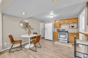 Kitchen featuring stainless steel range with electric cooktop, white fridge with ice dispenser, and light hardwood / wood-style flooring