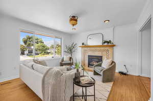 Living room with a tile fireplace, light hardwood / wood-style flooring, and ornamental molding